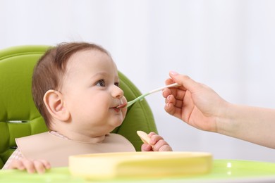 Photo of Mother feeding her baby on chair at home, closeup