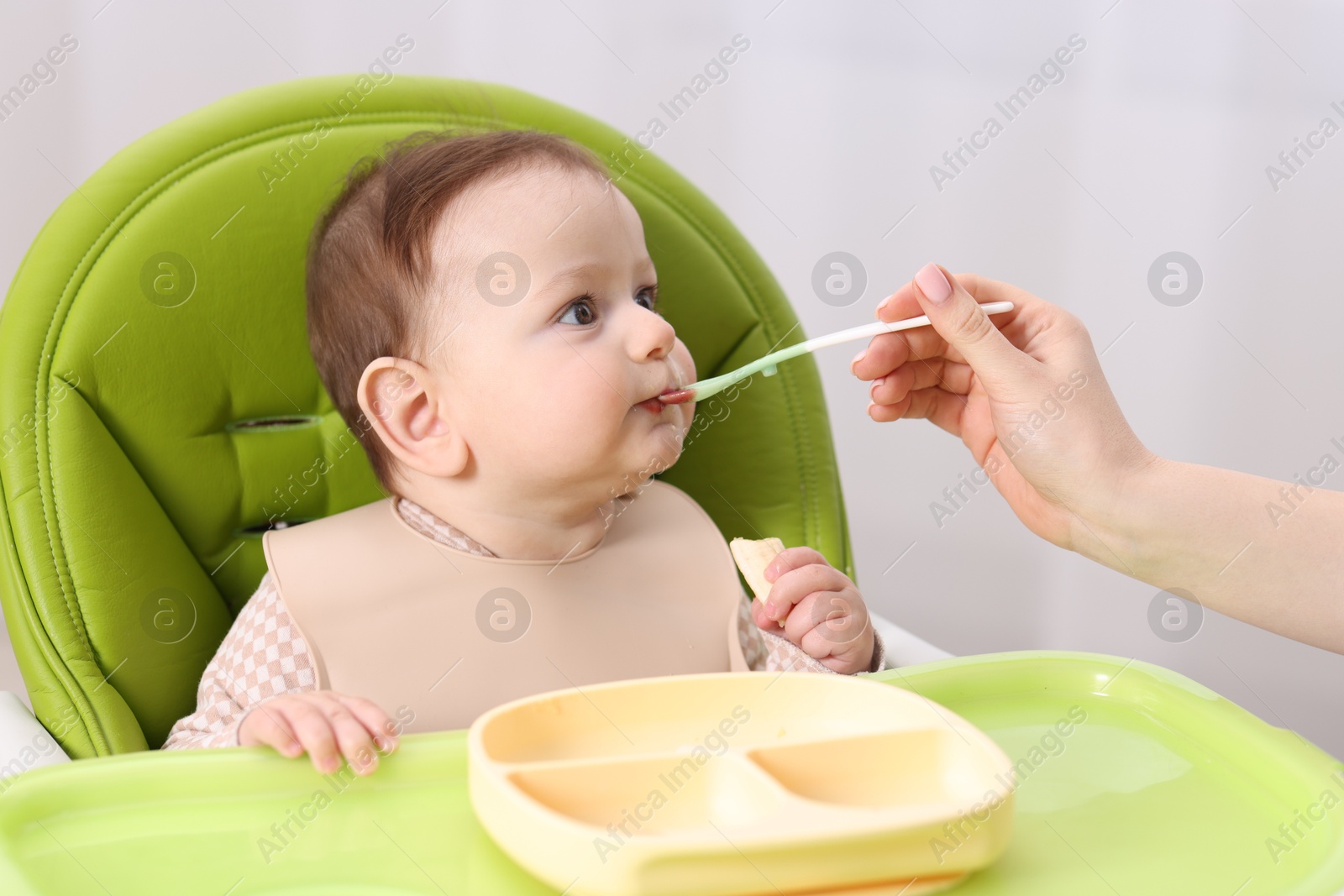 Mother feeding her baby on chair at home, closeup Photo of Mother feeding her baby on chair at home, closeup