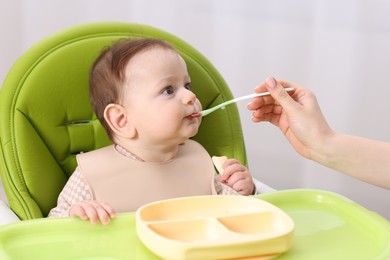 Photo of Mother feeding her baby on chair at home, closeup
