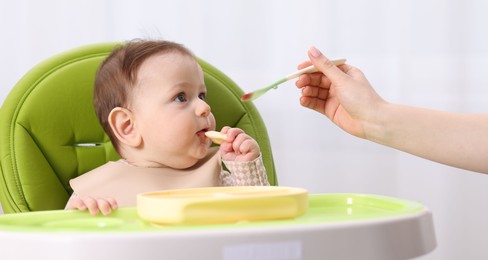 Photo of Mother feeding her baby on chair at home, closeup