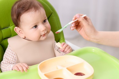 Photo of Mother feeding her baby on chair at home, closeup