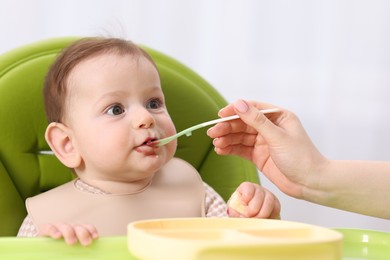 Photo of Mother feeding her baby on chair at home, closeup