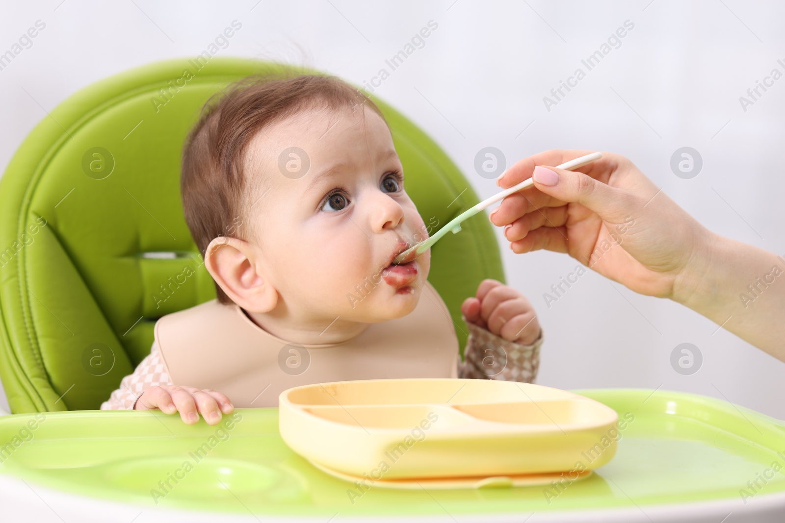 Mother feeding her baby on chair at home, closeup Photo of Mother feeding her baby on chair at home, closeup