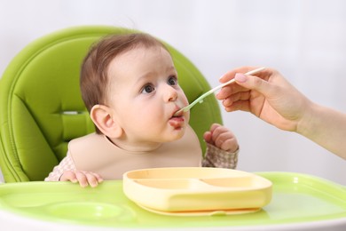 Photo of Mother feeding her baby on chair at home, closeup