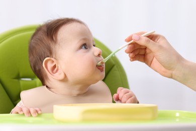 Photo of Mother feeding her baby on chair at home, closeup