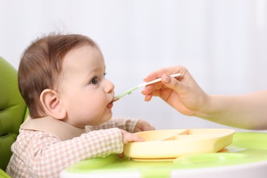 Photo of Mother feeding her baby on chair at home, closeup