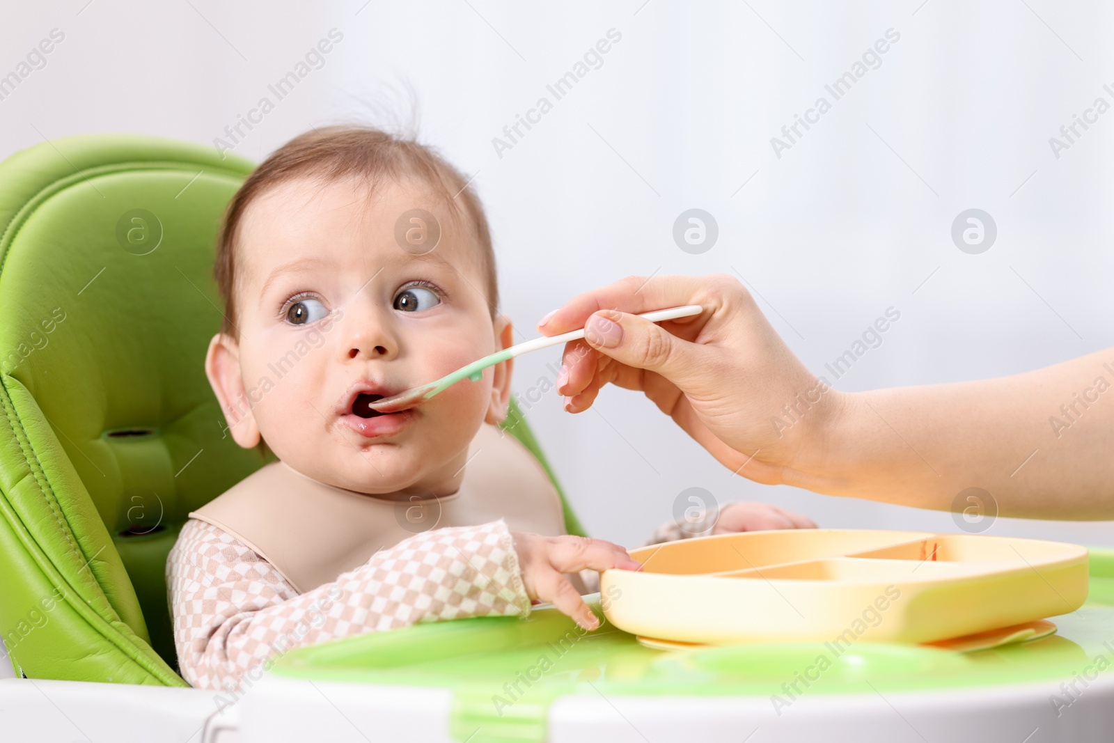 Mother feeding her baby on chair at home, closeup Photo of Mother feeding her baby on chair at home, closeup