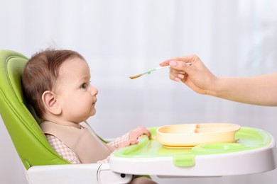 Photo of Mother feeding her baby on chair at home, closeup