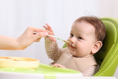 Photo of Mother feeding her baby on chair at home, closeup