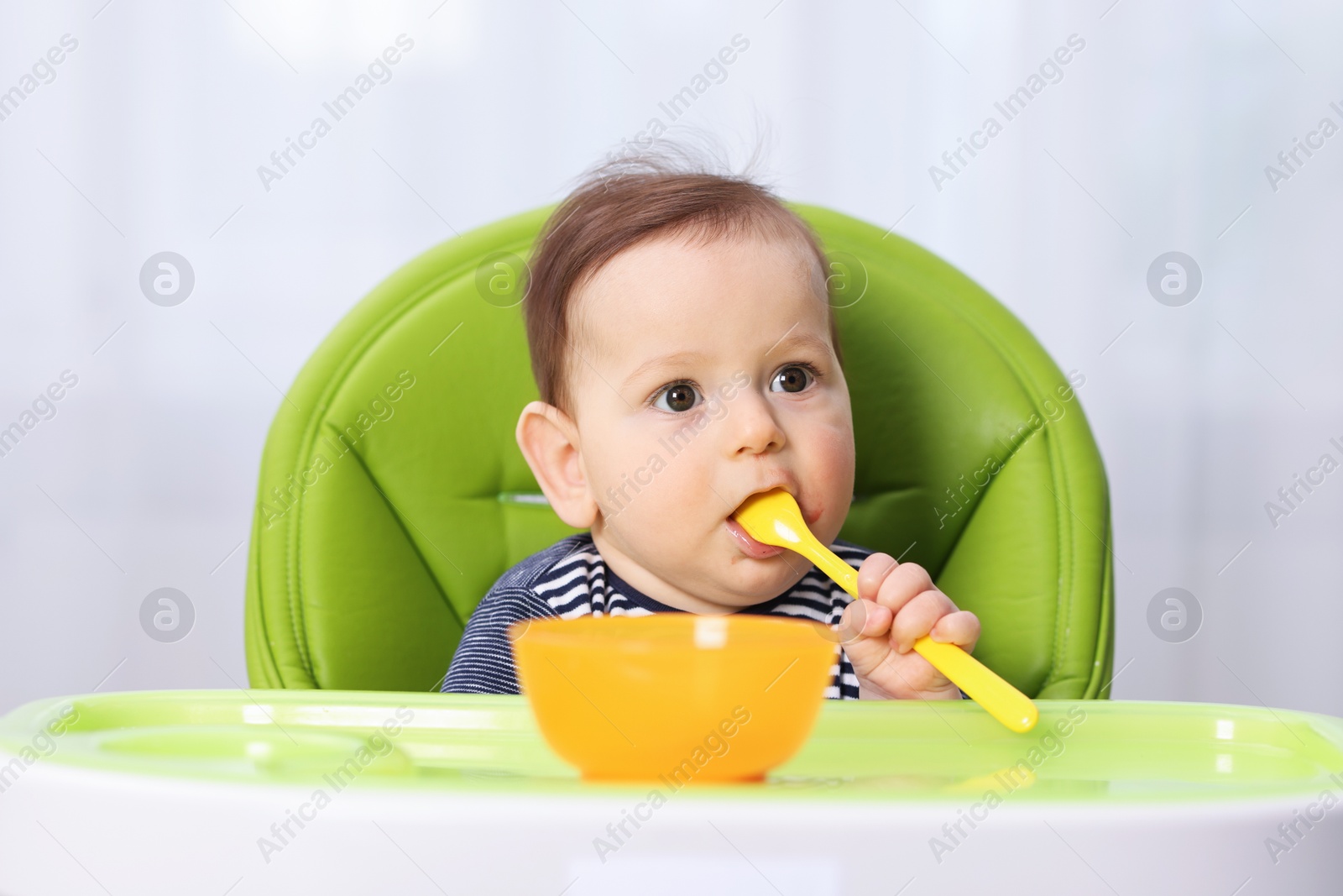Cute little baby eating on feeding chair at home Photo of Cute little baby eating on feeding chair at home