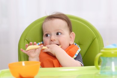 Photo of Cute little baby eating on feeding chair at home