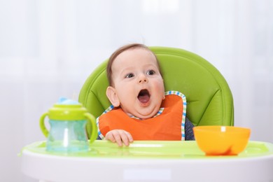 Photo of Cute little baby eating on feeding chair at home