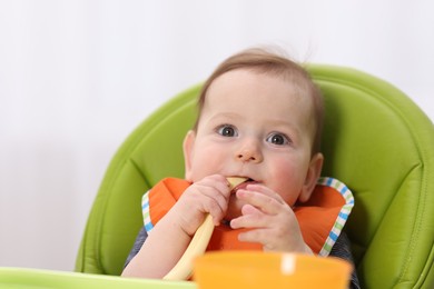 Photo of Cute little baby eating on feeding chair at home