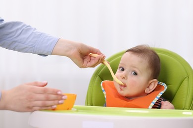 Photo of Mother feeding her baby on chair at home, closeup