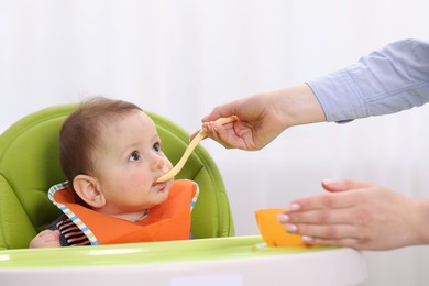 Photo of Mother feeding her baby on chair at home, closeup