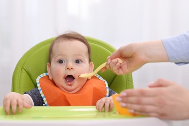 Photo of Mother feeding her baby on chair at home, closeup
