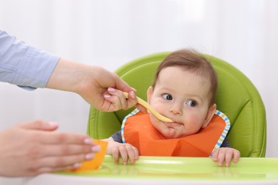 Photo of Mother feeding her baby on chair at home, closeup