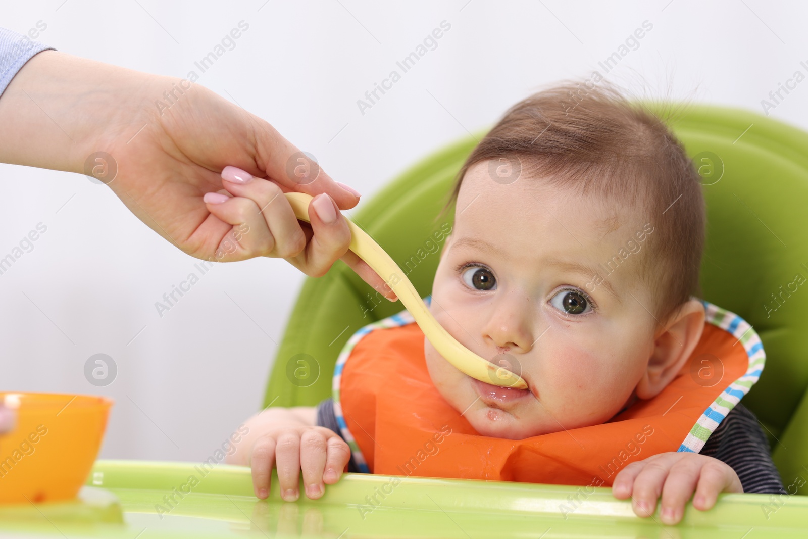 Mother feeding her baby on chair at home, closeup Photo of Mother feeding her baby on chair at home, closeup