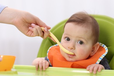 Photo of Mother feeding her baby on chair at home, closeup