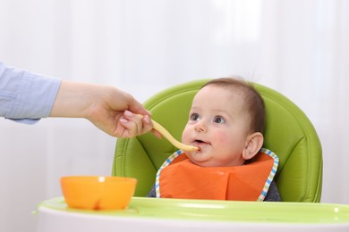Photo of Mother feeding her baby on chair at home, closeup