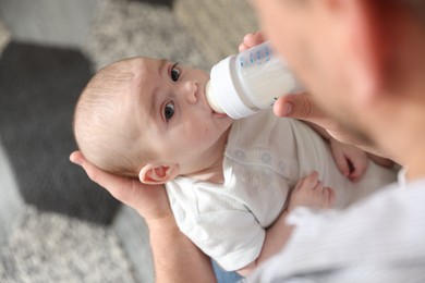 Photo of Father feeding his little baby with bottle at home, closeup