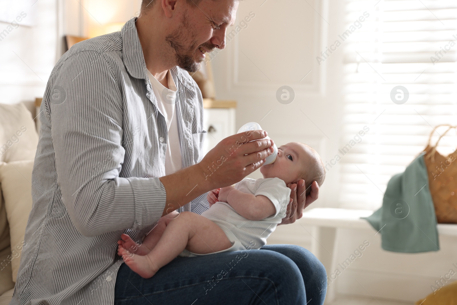 Father feeding his little baby with bottle on sofa at home, closeup Photo of Father feeding his little baby with bottle on sofa at home, closeup