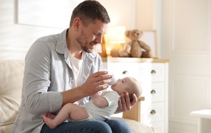 Photo of Father feeding his little baby with bottle on sofa at home. Space for text