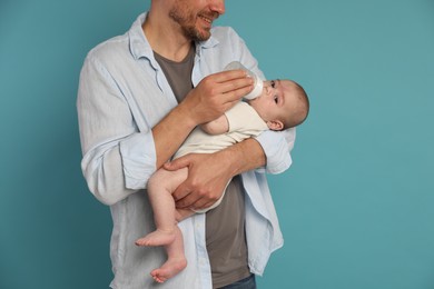 Photo of Father feeding his little baby with bottle on light blue background, closeup