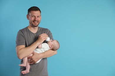 Photo of Father feeding his little baby with bottle on light blue background. Space for text