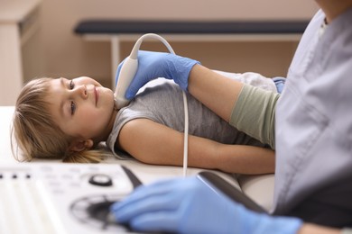 Photo of Sonographer conducting ultrasound examination of little girl's thyroid gland in clinic, closeup
