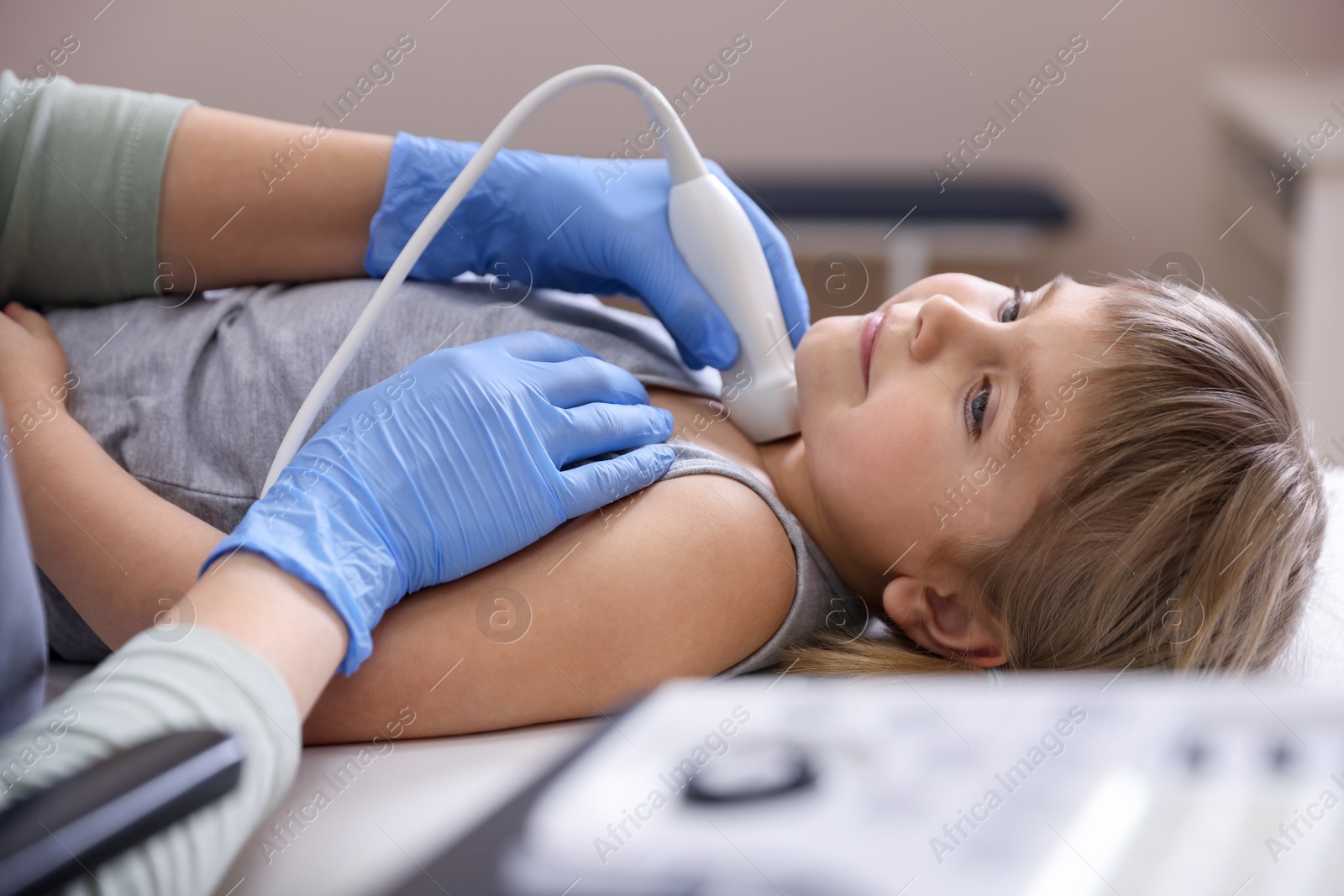 Sonographer conducting ultrasound examination of little girl's thyroid gland in clinic, closeup Photo of Sonographer conducting ultrasound examination of little girl's thyroid gland in clinic, closeup