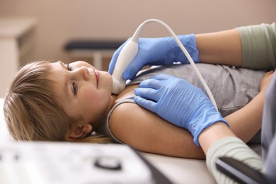 Photo of Sonographer conducting ultrasound examination of little girl's thyroid gland in clinic, closeup