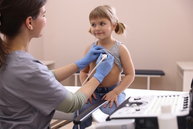 Photo of Sonographer conducting ultrasound examination of little girl's heart in clinic