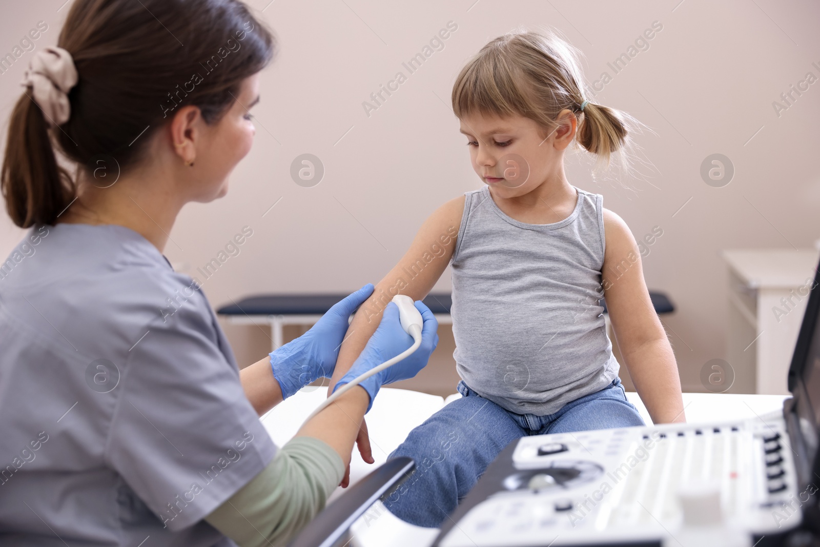 Sonographer conducting ultrasound examination of little girl's arm in clinic Photo of Sonographer conducting ultrasound examination of little girl's arm in clinic