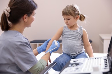 Photo of Sonographer conducting ultrasound examination of little girl's arm in clinic