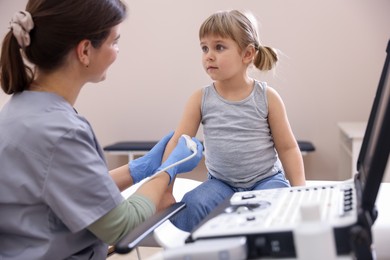 Photo of Sonographer conducting ultrasound examination of little girl's arm in clinic
