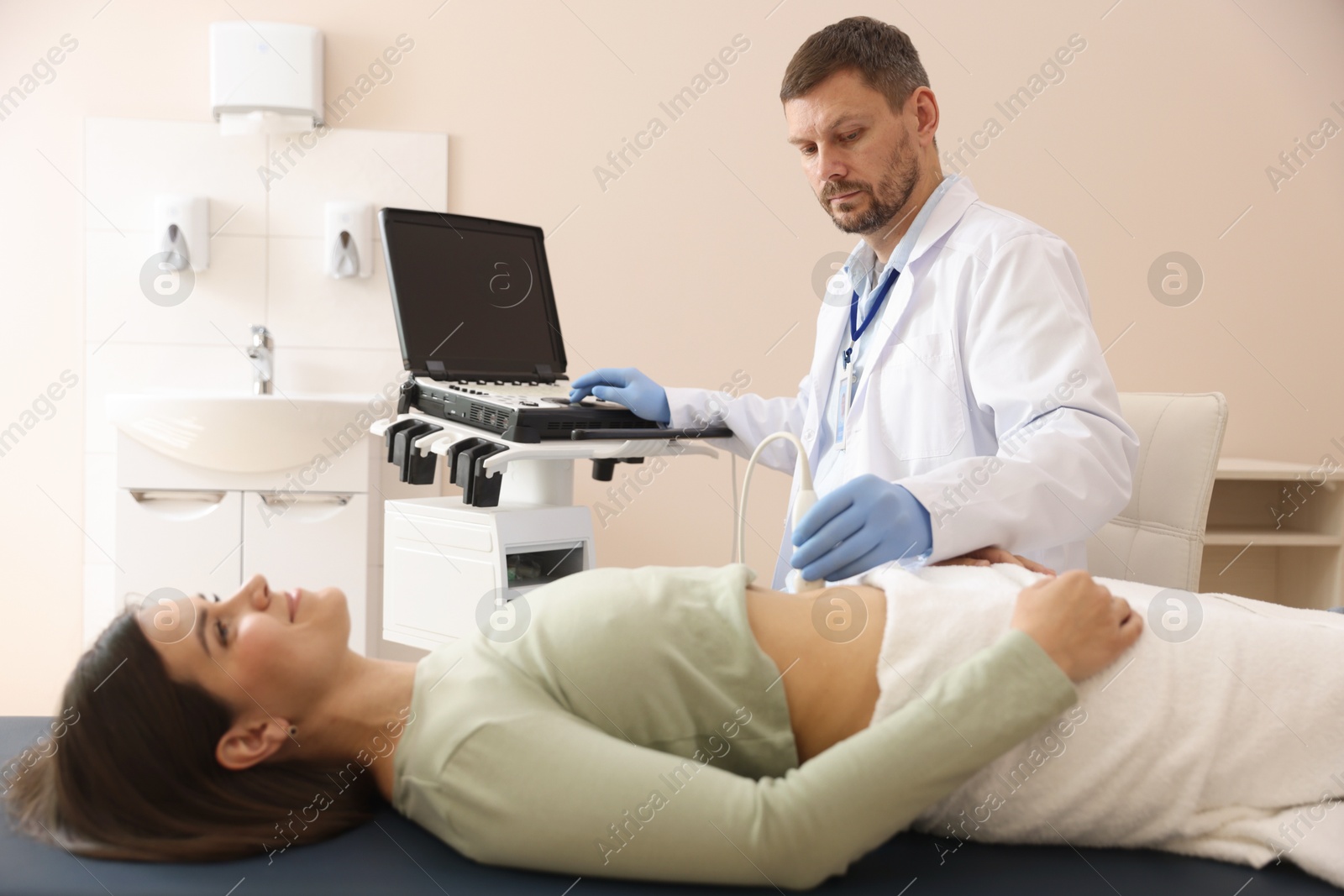 Sonographer conducting woman's abdominal ultrasound examination in clinic Photo of Sonographer conducting woman's abdominal ultrasound examination in clinic