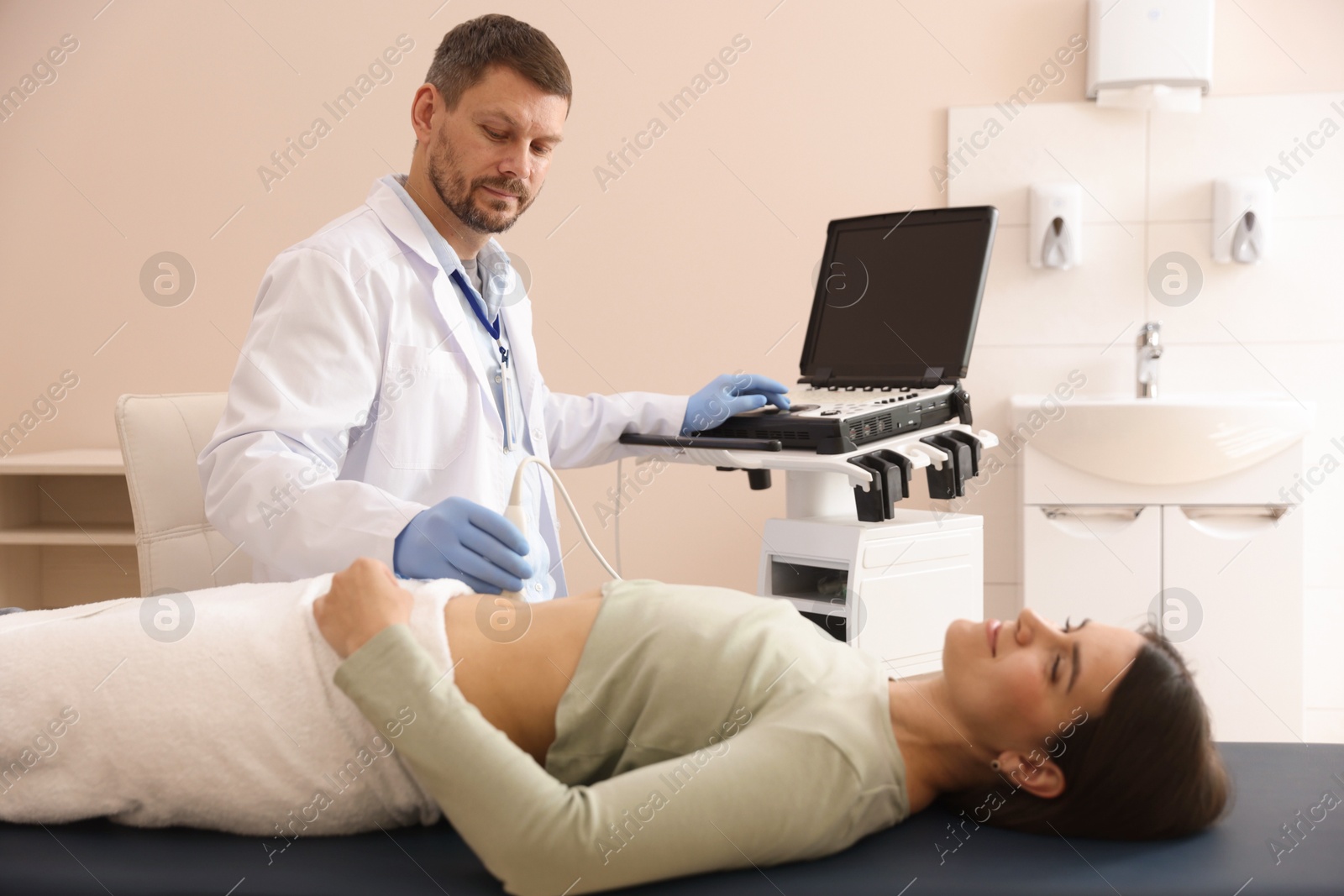 Sonographer conducting woman's abdominal ultrasound examination in clinic Photo of Sonographer conducting woman's abdominal ultrasound examination in clinic
