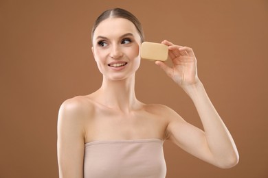 Photo of Smiling woman with soap bar on brown background