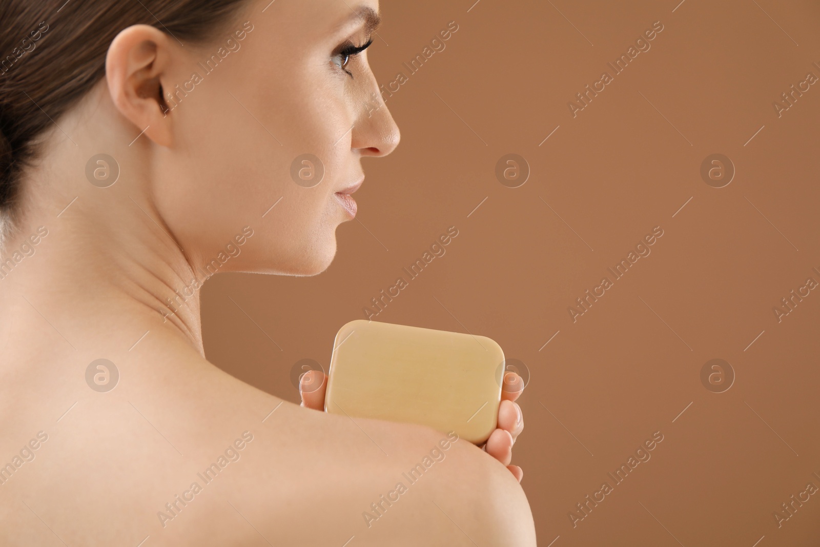Woman with soap bar on brown background, closeup. Space for text Photo of Woman with soap bar on brown background, closeup. Space for text