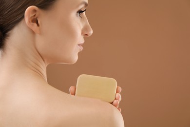 Photo of Woman with soap bar on brown background, closeup. Space for text