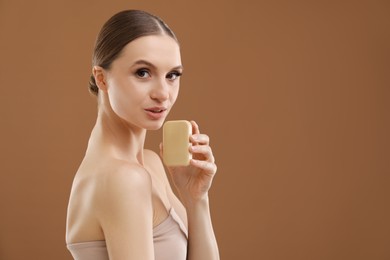 Photo of Beautiful woman with soap bar on brown background. Space for text