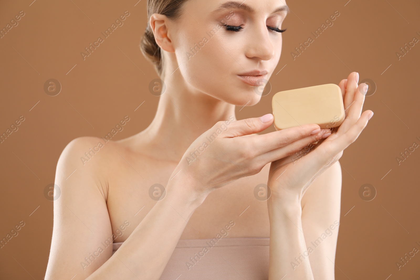 Beautiful woman with soap bar on brown background, closeup Photo of Beautiful woman with soap bar on brown background, closeup