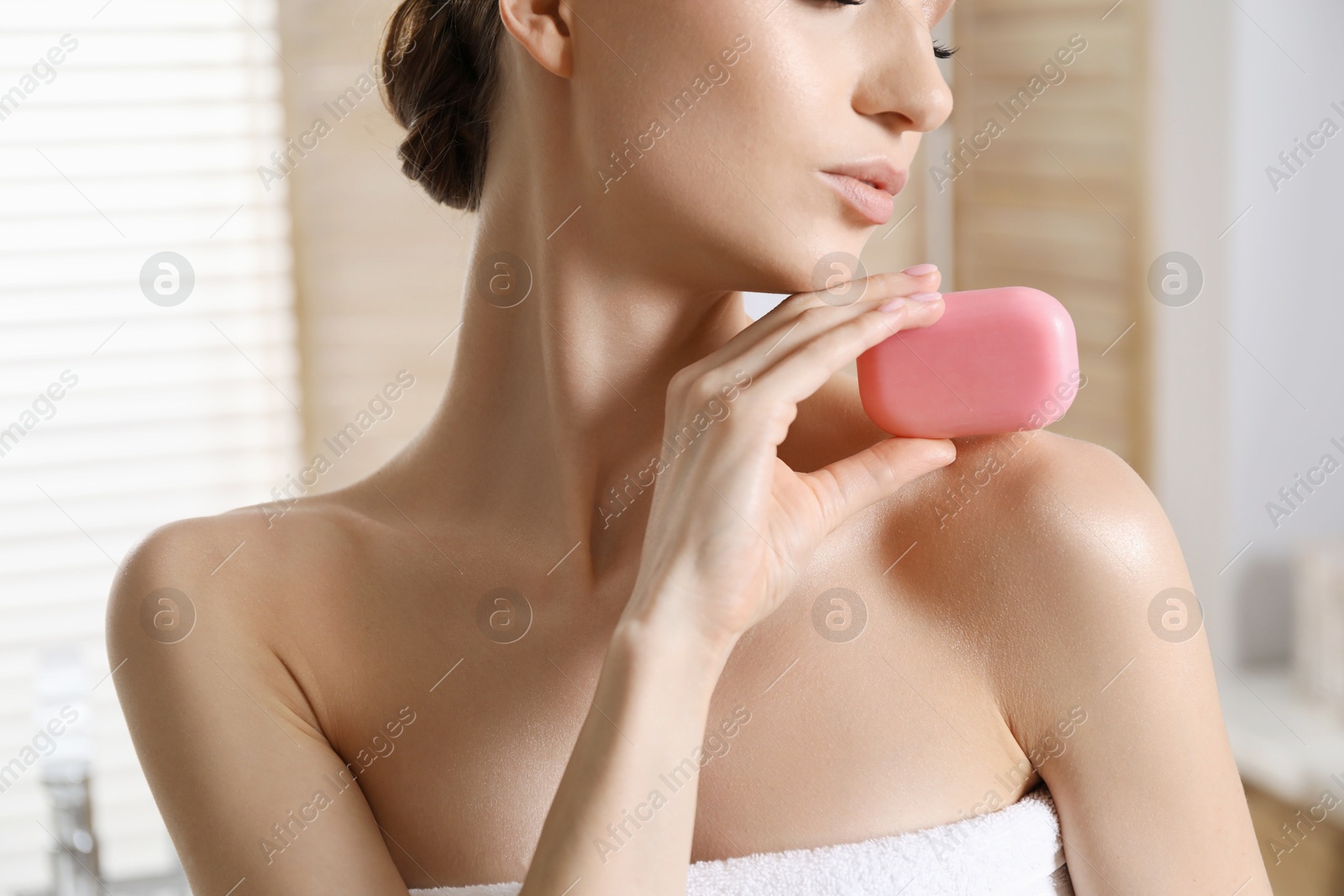 Photo of Woman with soap bar in bathroom, closeup