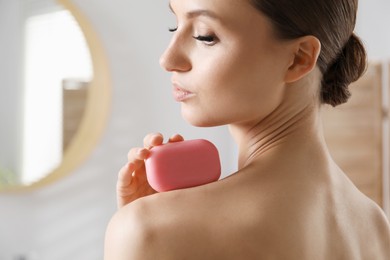 Photo of Beautiful woman with soap bar in bathroom, closeup