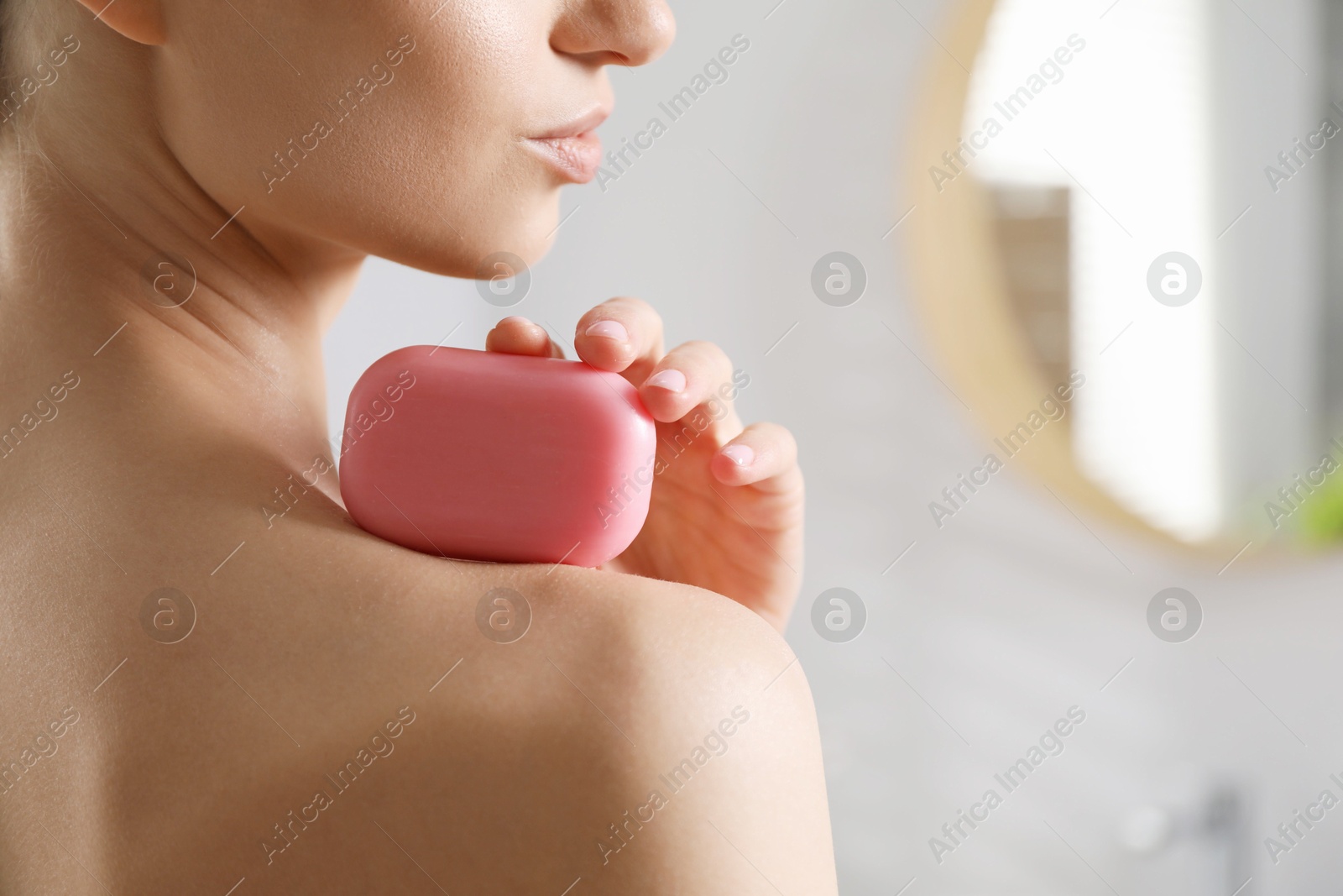 Photo of Woman with soap bar in bathroom, closeup