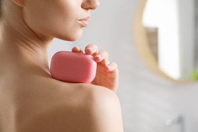 Photo of Woman with soap bar in bathroom, closeup