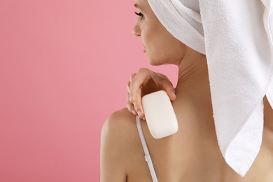 Photo of Woman with soap bar on pink background, closeup. Space for text