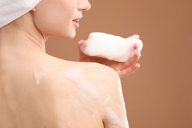 Photo of Woman with soap bar on brown background, closeup