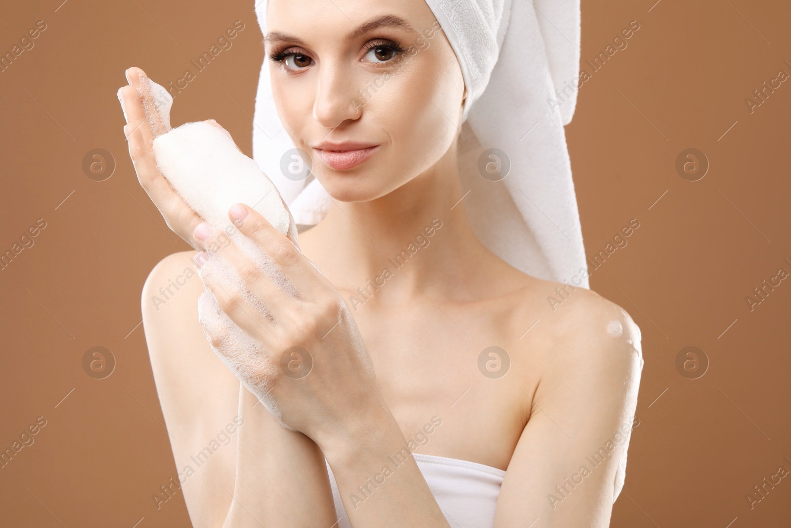 Beautiful woman with soap bar on brown background, closeup Photo of Beautiful woman with soap bar on brown background, closeup